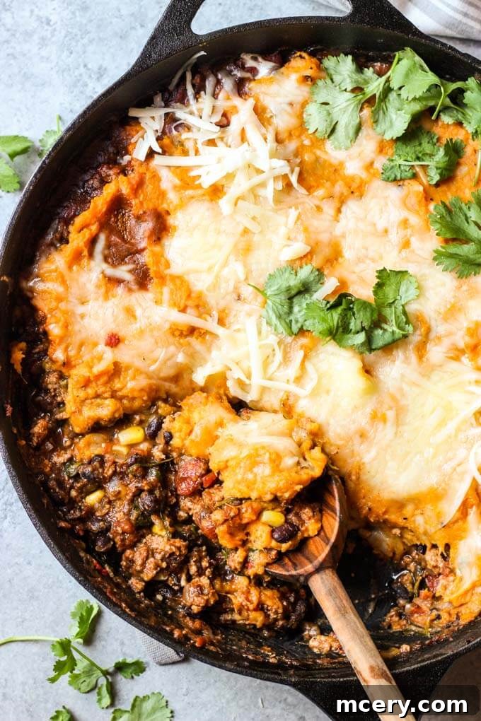 Golden Mash Comfort Bake 2 Close up of sweet potato shepherd's pie in cast iron skillet, showcasing the cheesy sweet potato topping and rich filling
