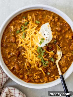 turkey pumpkin chili in a bowl with cheese and green onions.