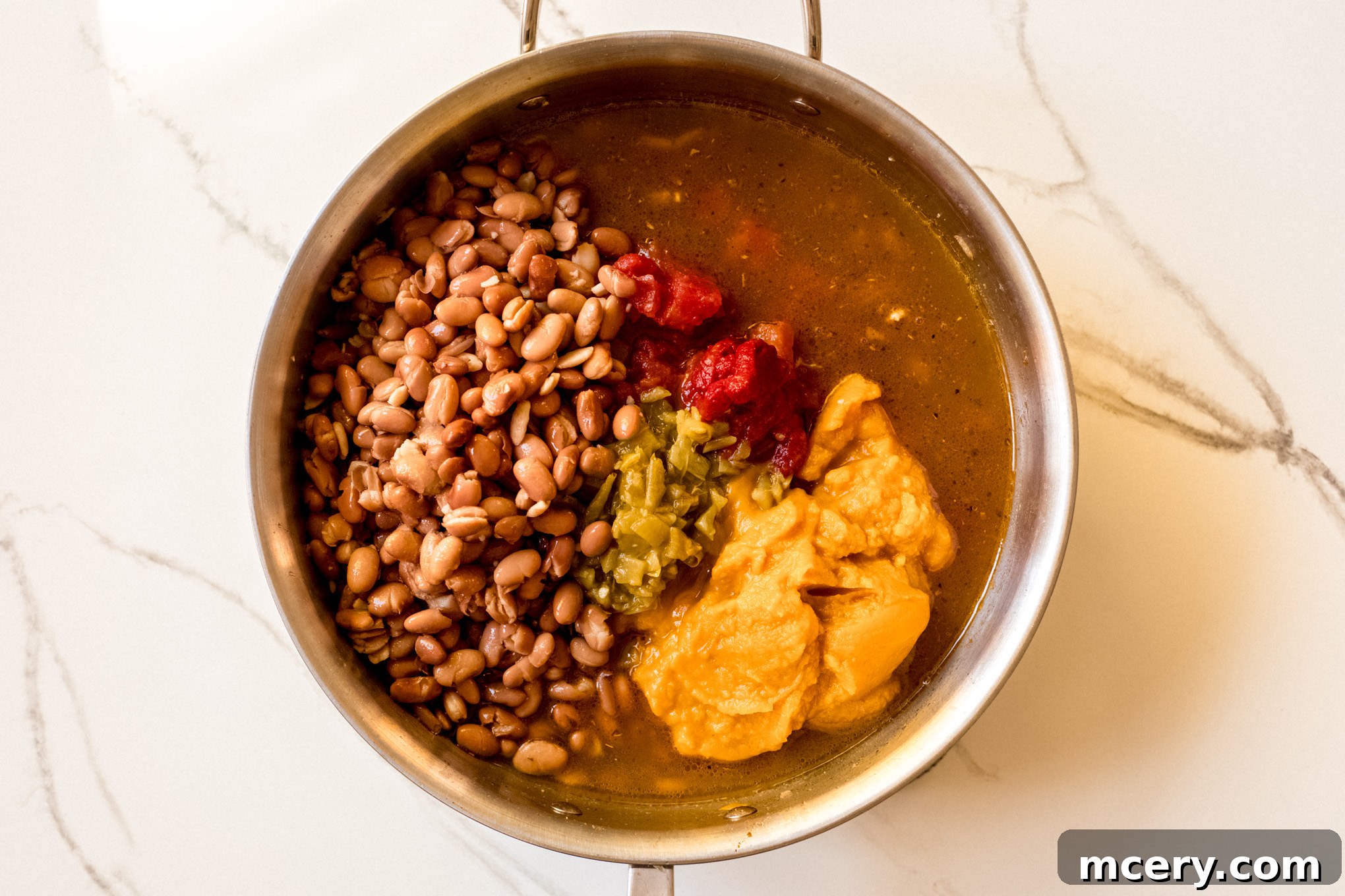 Pumpkin Harvest Turkey Chili 7 Beans, pumpkin puree, and tomatoes in a pot with cooked turkey.