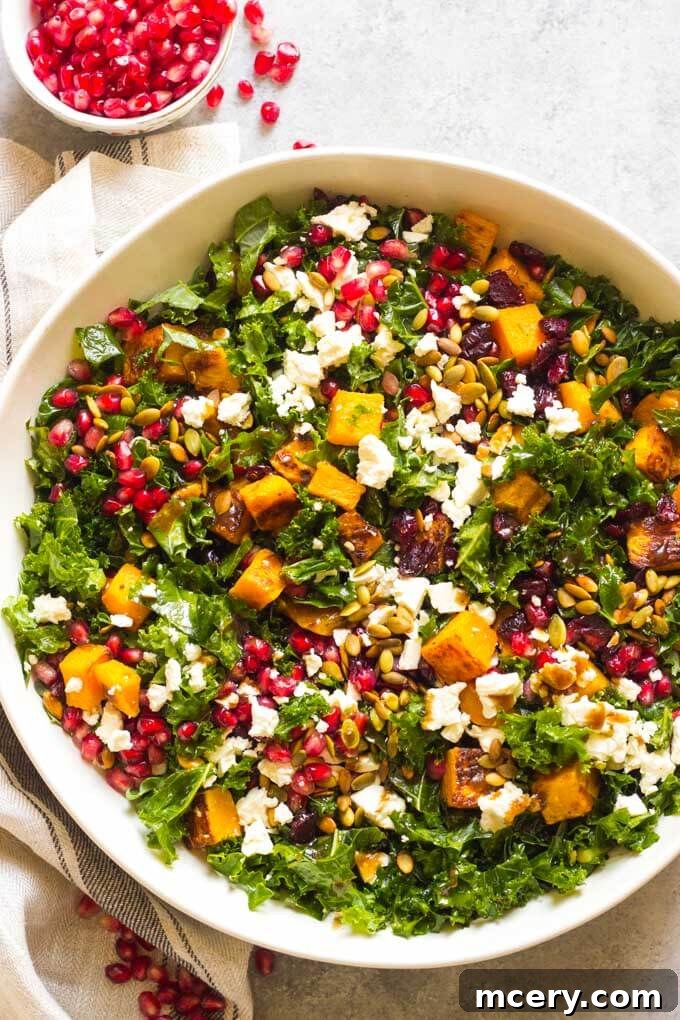 Sweet-Tart Kale and Cranberry Salad 2 A vibrant close-up of a festive kale salad in a white bowl, featuring roasted butternut squash, bright red cranberries, green pumpkin seeds, pomegranate arils, and crumbled feta cheese, all glistening with balsamic dressing. Perfect for fall gatherings and Thanksgiving.