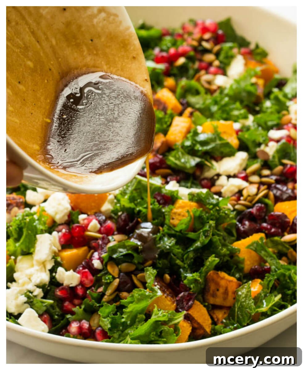 Sweet-Tart Kale and Cranberry Salad 7 A close-up shot of the finished kale salad, colorful and inviting, with a hand pouring additional balsamic dressing over the top just before serving, highlighting its fresh ingredients.