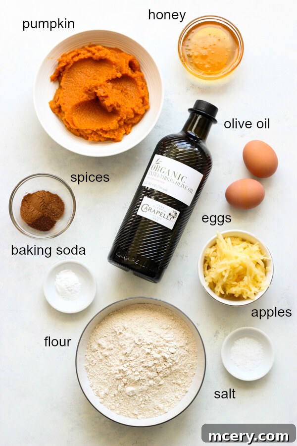 Clean Eating Pumpkin Loaf 3 A vibrant display of fresh and dry ingredients arranged for making healthy pumpkin bread, including spices, flour, pumpkin puree, and apples.