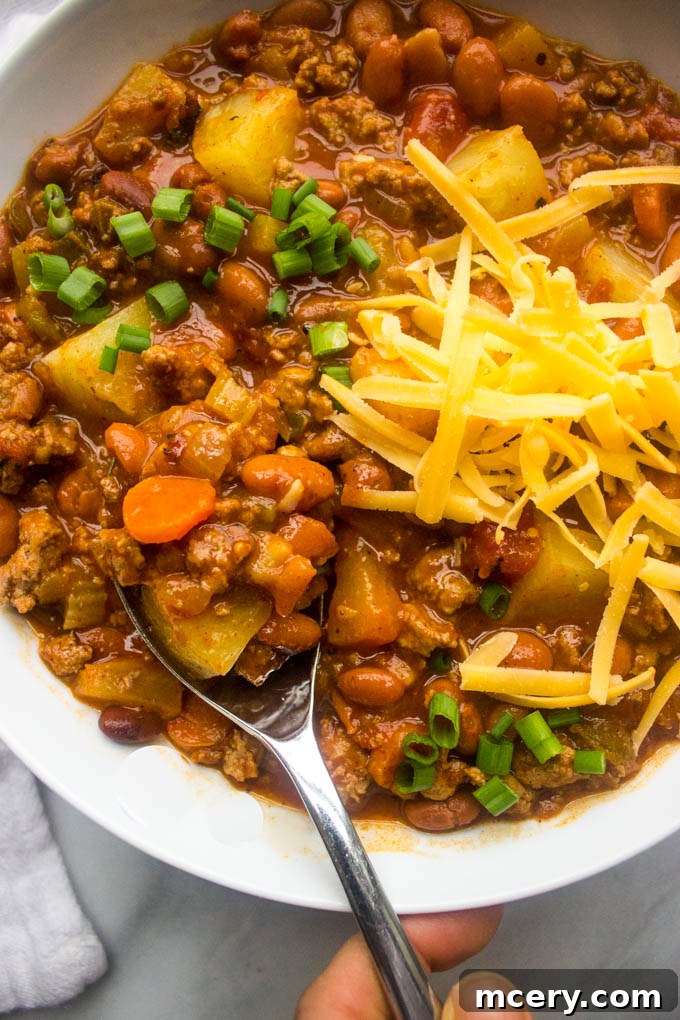 Side close up view of sweet and spicy chili in a white bowl, showing its rich texture.