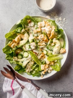 A beautifully presented Caesar salad in a bowl with a side of creamy Greek yogurt dressing, ready to be served.