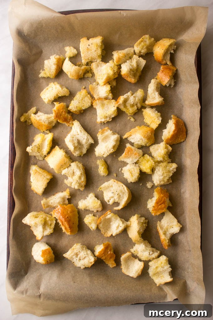 Lush Avocado Caesar 7 Homemade croutons spread evenly on a parchment-lined baking sheet, ready for baking until golden and crisp.