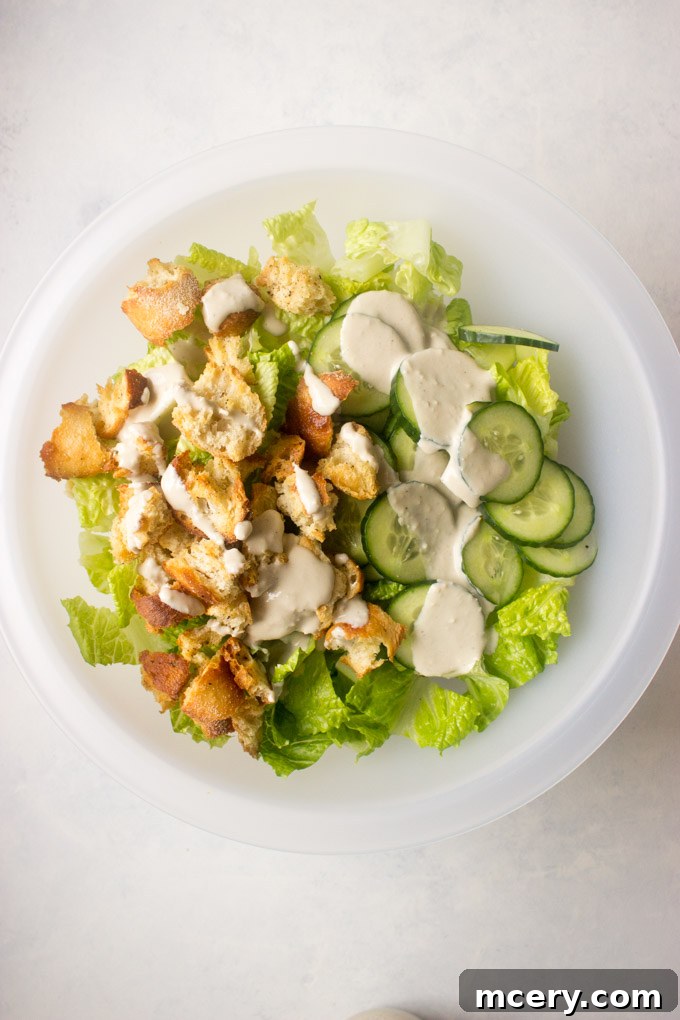 Lush Avocado Caesar 8 A large salad bowl filled with chopped romaine lettuce, thinly sliced cucumbers, and golden croutons, all coated in the creamy Caesar dressing.