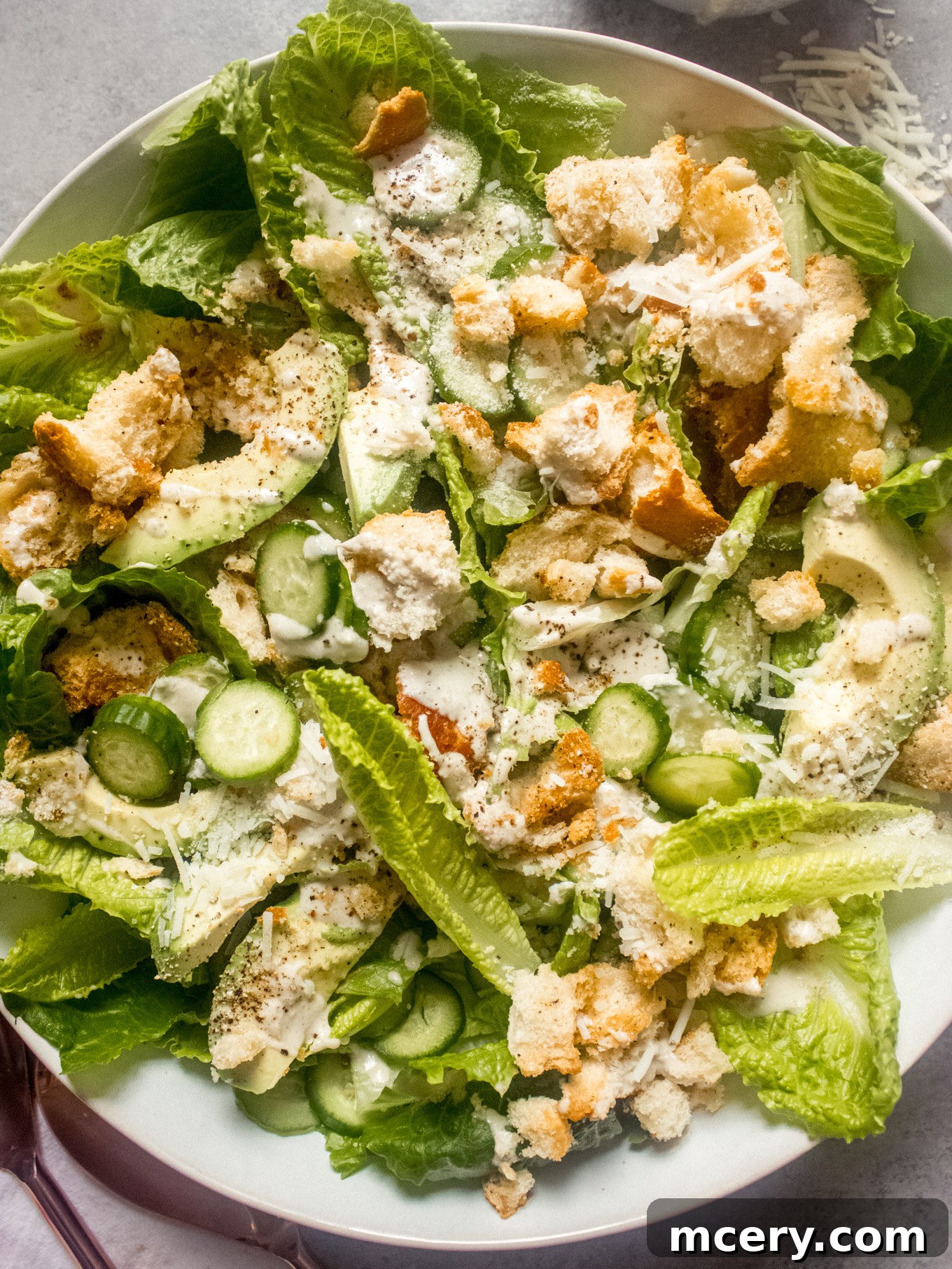 Lush Avocado Caesar 10 A close-up shot of the Avocado Caesar Salad, garnished with a light drizzle of dressing and freshly grated Parmesan cheese, highlighting its appealing texture.