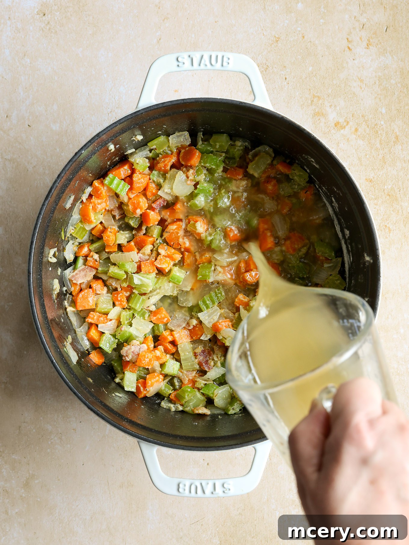 Velvety Scallop Chowder 7 Chicken stock being poured into the Dutch oven with the roux and vegetables.
