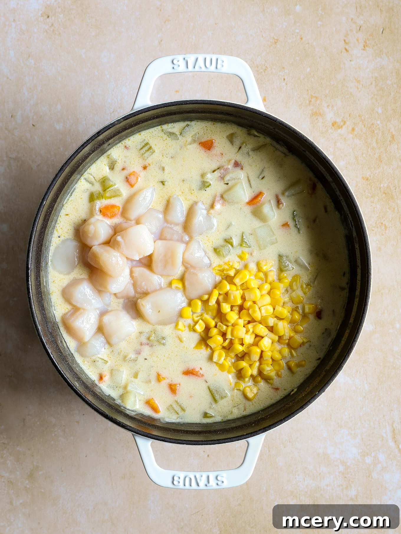Velvety Scallop Chowder 9 Bay scallops and corn being stirred into the creamy chowder in a Dutch oven.