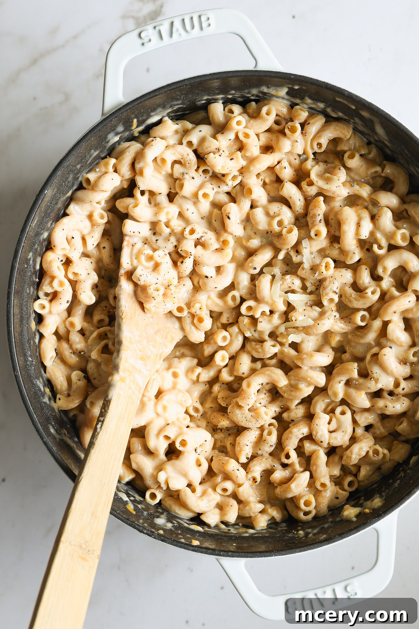 Guilt Free Whole Wheat Mac and Cheese 2 Creamy whole wheat mac and cheese served in a rustic Dutch oven with a wooden spoon, ready to be enjoyed.