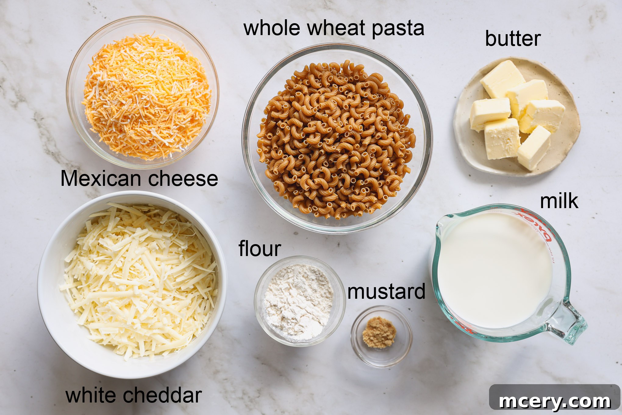 Guilt Free Whole Wheat Mac and Cheese 3 Individual ingredients laid out for making stovetop mac and cheese, including whole wheat pasta, cheeses, milk, butter, and spices.