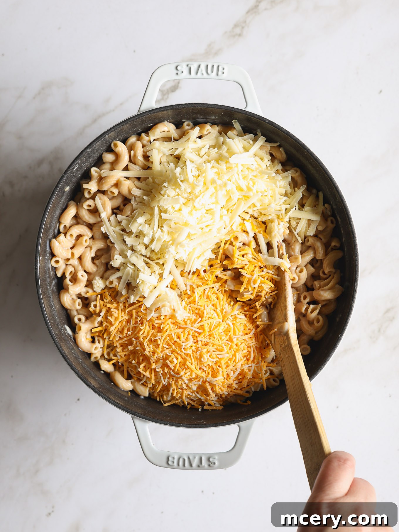 Guilt Free Whole Wheat Mac and Cheese 7 Shredded cheddar and Mexican blend cheese melting over cooked macaroni in a Dutch oven.