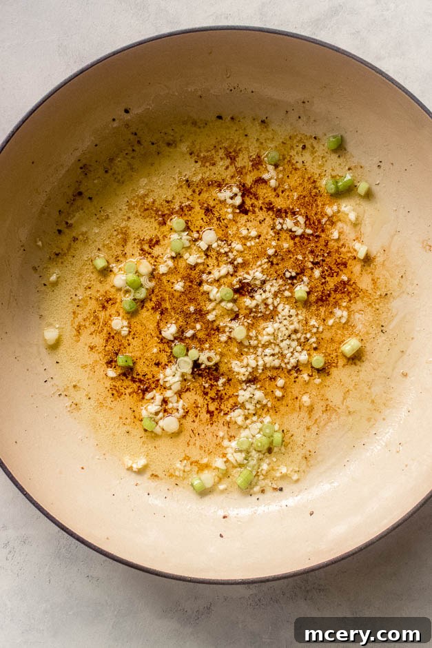 Creamy Coconut Chicken Skillet 7 Minced garlic and white parts of green onions sautéing in a pan.