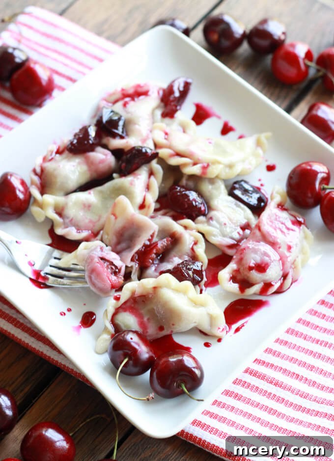 Ruby Cherry Vareniki 9 A close-up of beautifully cooked cherry vareniki served on a white plate, garnished with fresh cherries and a drizzle of cherry compote.