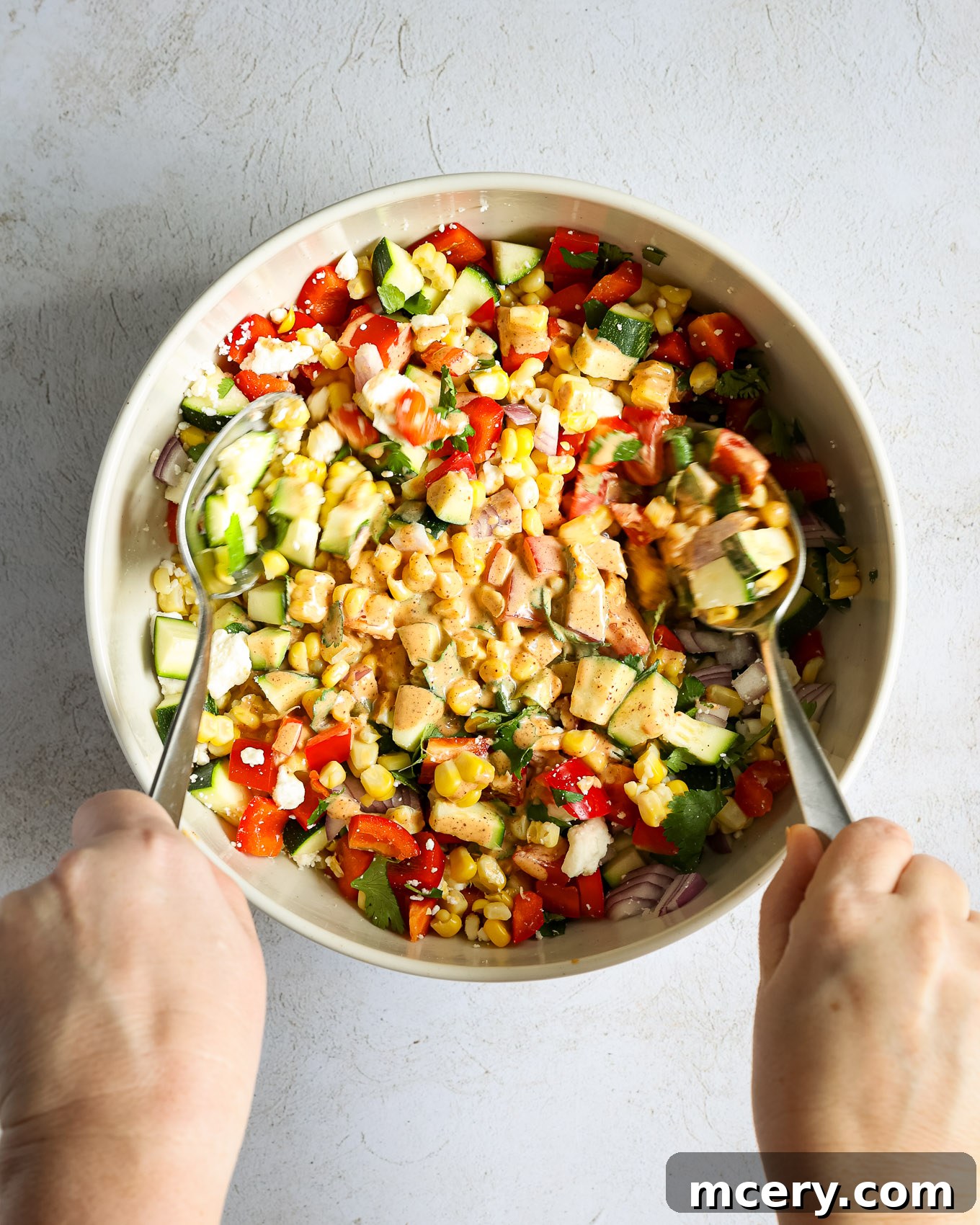 Vibrant Zucchini Corn Medley 7 A hand tossing the zucchini corn salad with the creamy dressing to combine all ingredients.