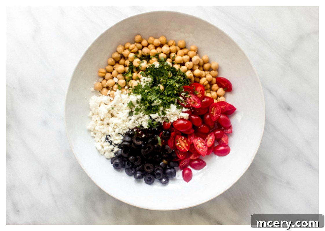 Mediterranean Sunshine Chickpea Salad 4 Prepared ingredients for an easy chickpea salad in a large white mixing bowl, before dressing.