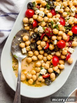 Close up of a Greek-style chickpea salad with oregano vinaigrette, featuring feta, tomatoes, and olives.