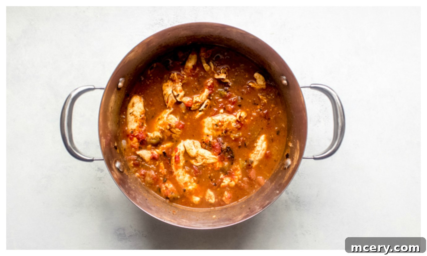 Simple Skillet Creamy Shredded Chicken 5 Overhead view of perfectly cooked chicken tenders simmering in a rich, flavorful sauce inside a Dutch oven.