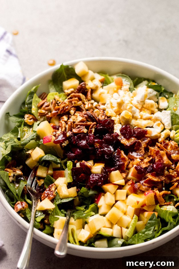 Vibrant Apple Spinach Medley 3 Spinach and apple salad generously portioned in a white bowl, showcasing the mix of bacon, cranberries, goat cheese, and a glossy balsamic vinaigrette.
