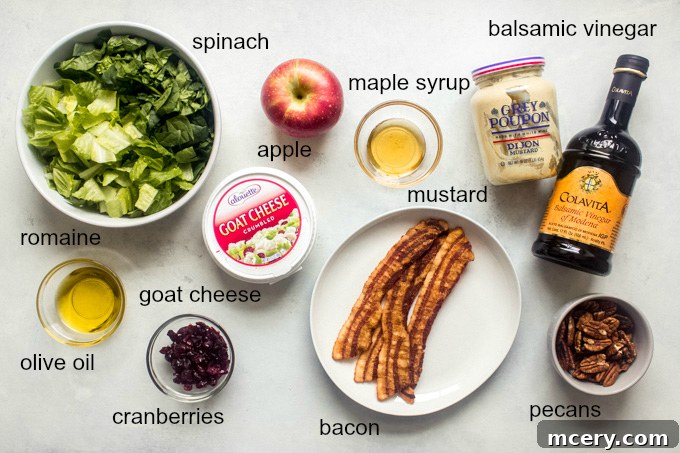Vibrant Apple Spinach Medley 4 Arrangement of fresh ingredients for spinach apple salad including spinach, romaine, apples, bacon, pecans, cranberries, and goat cheese on a wooden board.