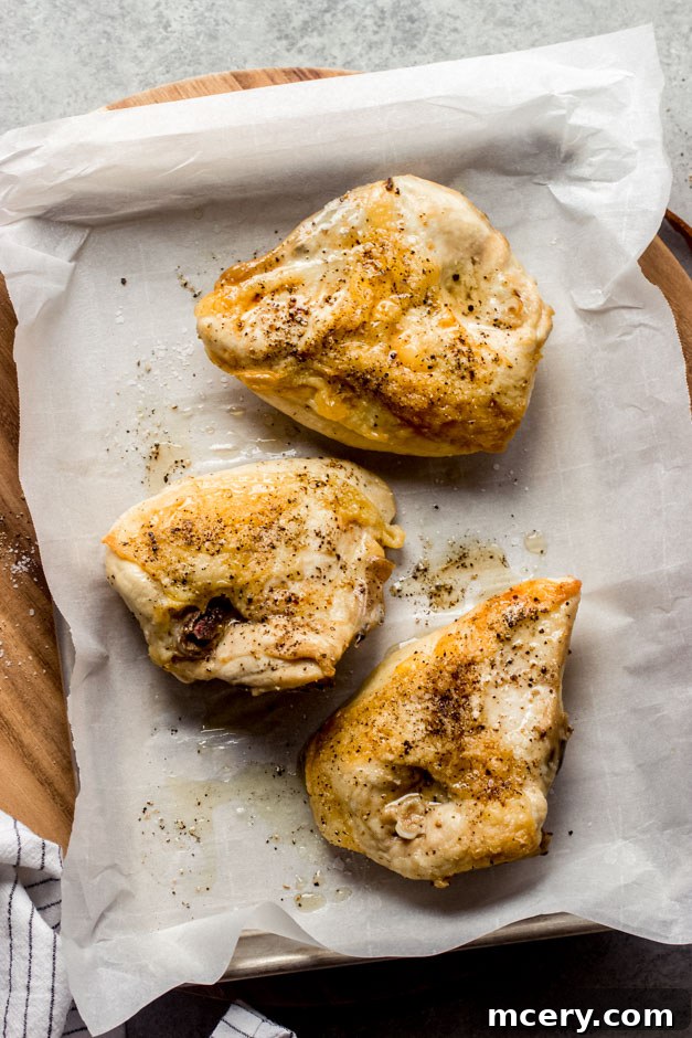 Succulent Oven Roasted Bone-In Chicken Breast 2 Perfectly golden-brown roasted bone-in chicken breasts on a baking sheet, ready to be served.