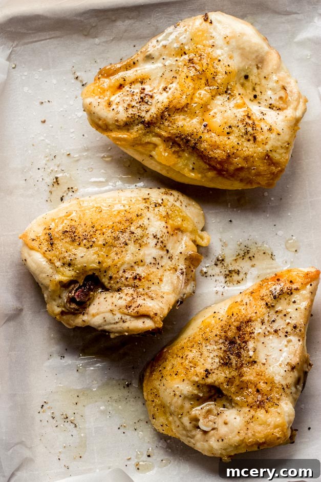 Succulent Oven Roasted Bone-In Chicken Breast 4 Two beautifully roasted bone-in chicken breasts on a baking sheet, golden and juicy, ready to be carved.