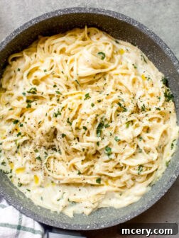 Creamy garlic sauce recipe, served in a skillet with a spoon, ready for pasta.