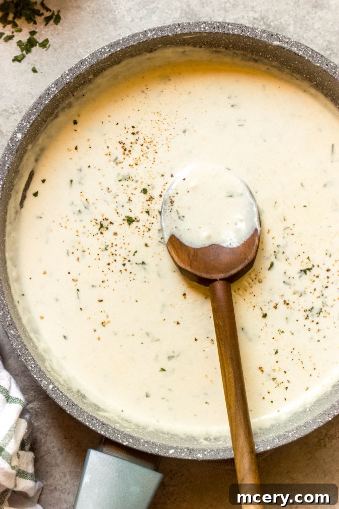 Creamy garlic sauce poured over freshly cooked pasta in a bowl, ready to be tossed.