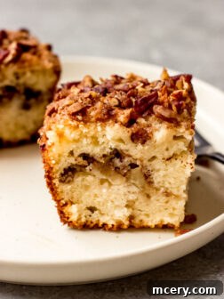 A beautifully sliced piece of sour cream apple cake with a generous crumble topping