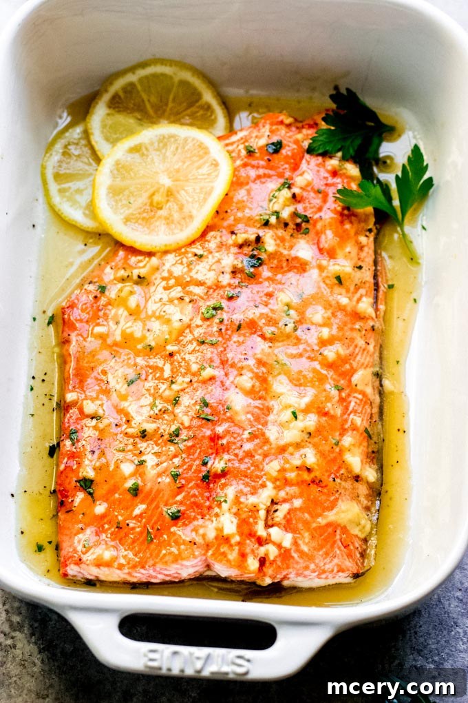 maple mustard salmon in a baking dish with sliced lemons and fresh parsley.