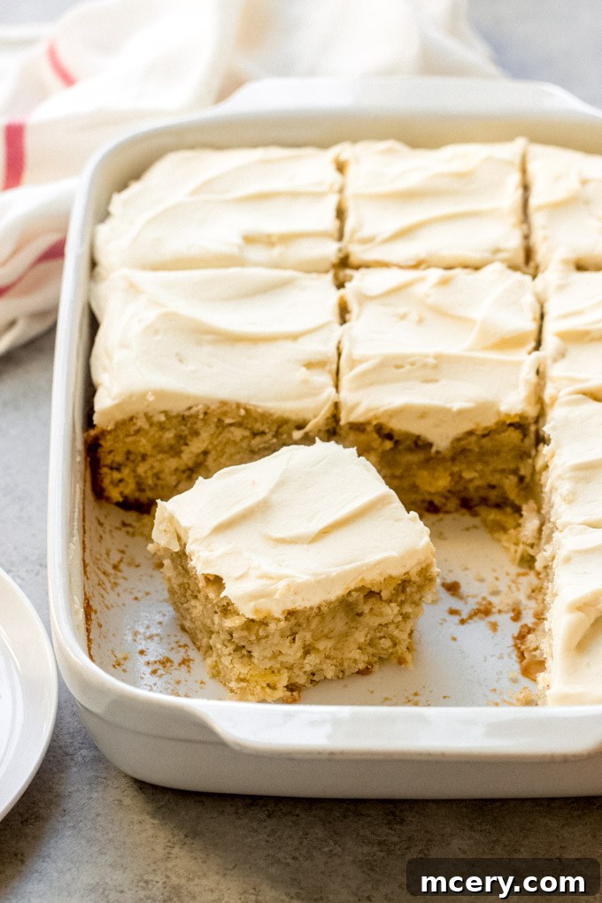 Southern Hummingbird Slab Cake 12 A slice of Hummingbird Sheet Cake, showing its moist crumb and delicious cream cheese frosting, garnished with coconut flakes.