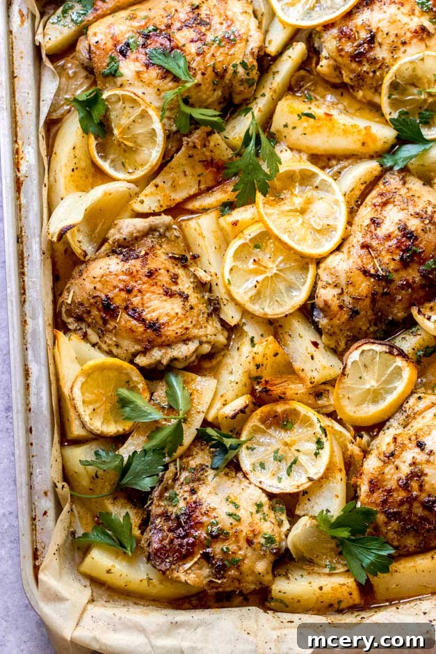 Zesty Lemon Herb Roasted Chicken and Golden Potatoes 3 Close-up of golden brown roasted chicken thighs nestled among tender potatoes, glistening with lemon and herb seasoning