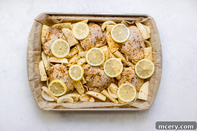 Zesty Lemon Herb Roasted Chicken and Golden Potatoes 8 Cooked lemon roasted chicken thighs, topped with fresh lemon slices, surrounded by tender potatoes and onions in a baking pan