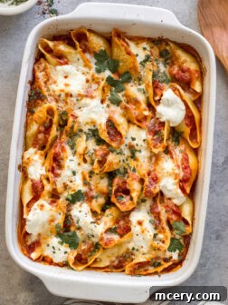 Delicious baked Italian sausage stuffed shells with melted cheese and fresh marinara sauce in a white baking dish.