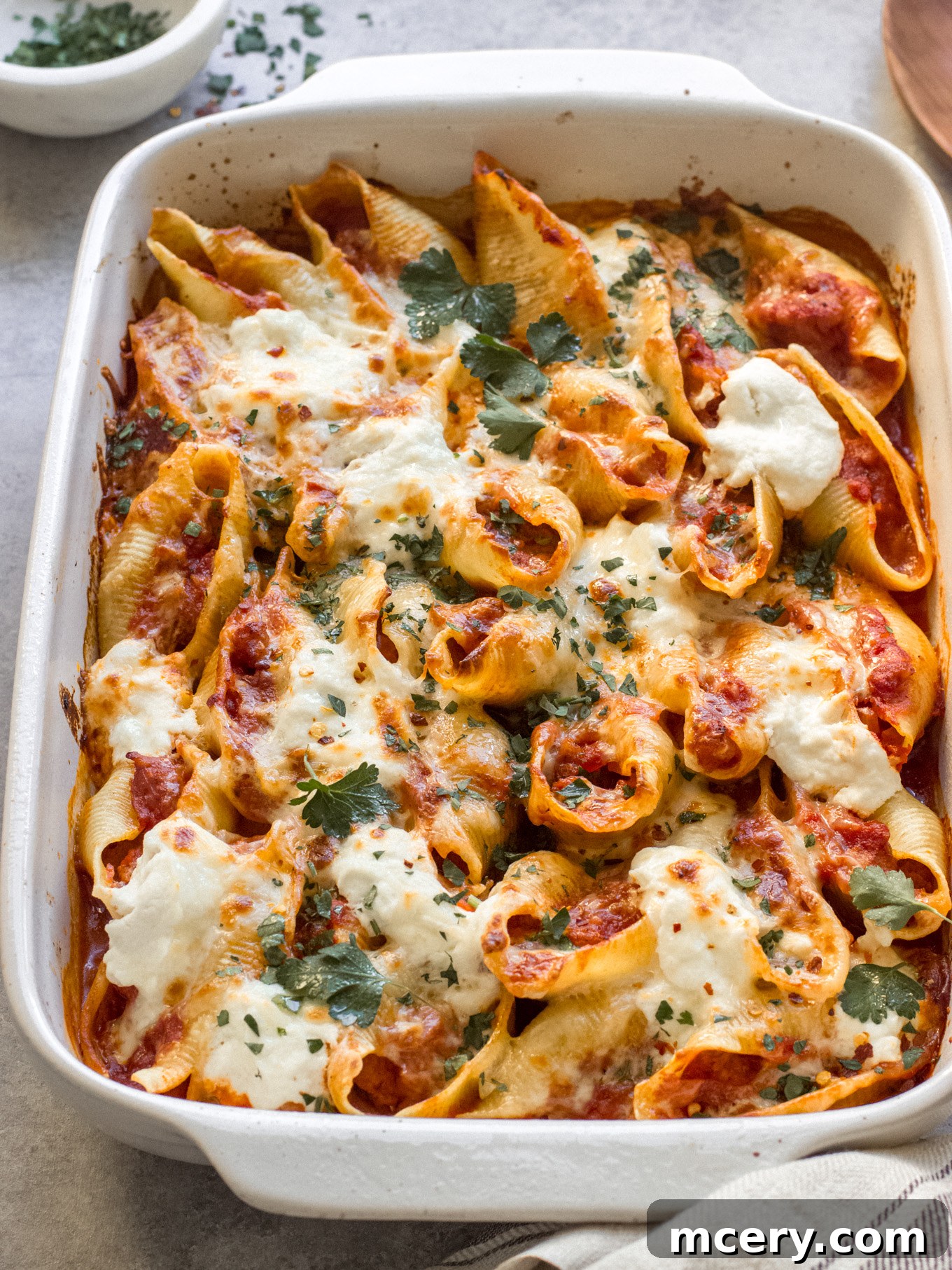Golden Baked Italian Sausage Stuffed Shells 9 Close-up of a large white baking dish filled with golden-brown Italian sausage stuffed shells, ready to be served.