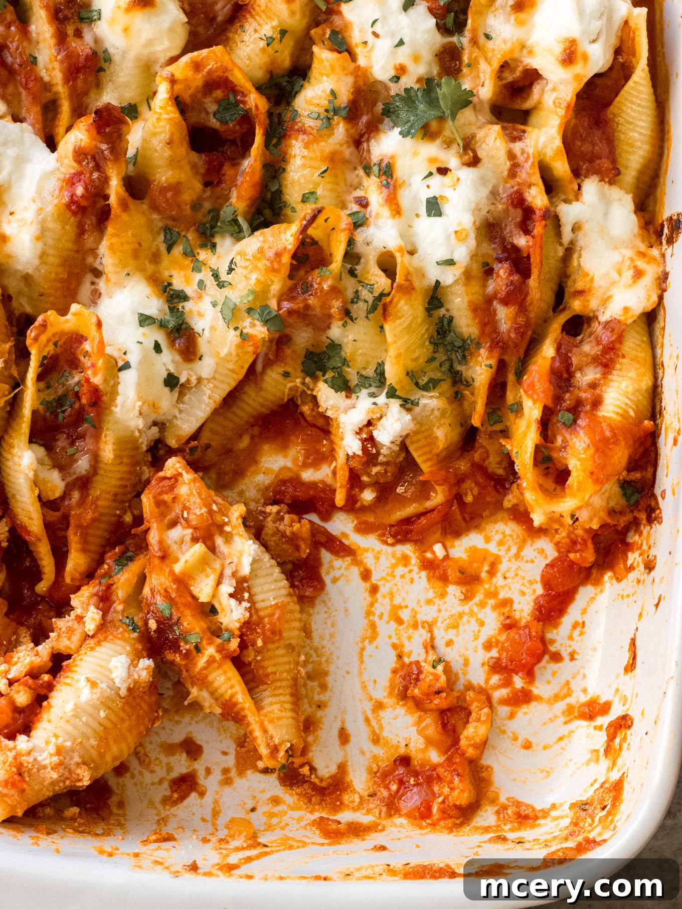 Golden Baked Italian Sausage Stuffed Shells 10 Close-up of a single Italian sausage stuffed shell, showcasing the rich meat and cheese filling, with melted mozzarella and fresh parsley garnish.