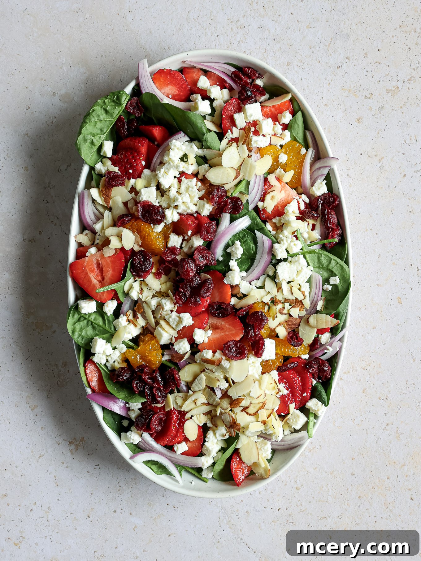 Vibrant Strawberry Chicken Salad 4 A vibrant array of sliced strawberries, mandarin oranges, feta cheese crumbles, almonds, and dried cranberries layered over spinach.
