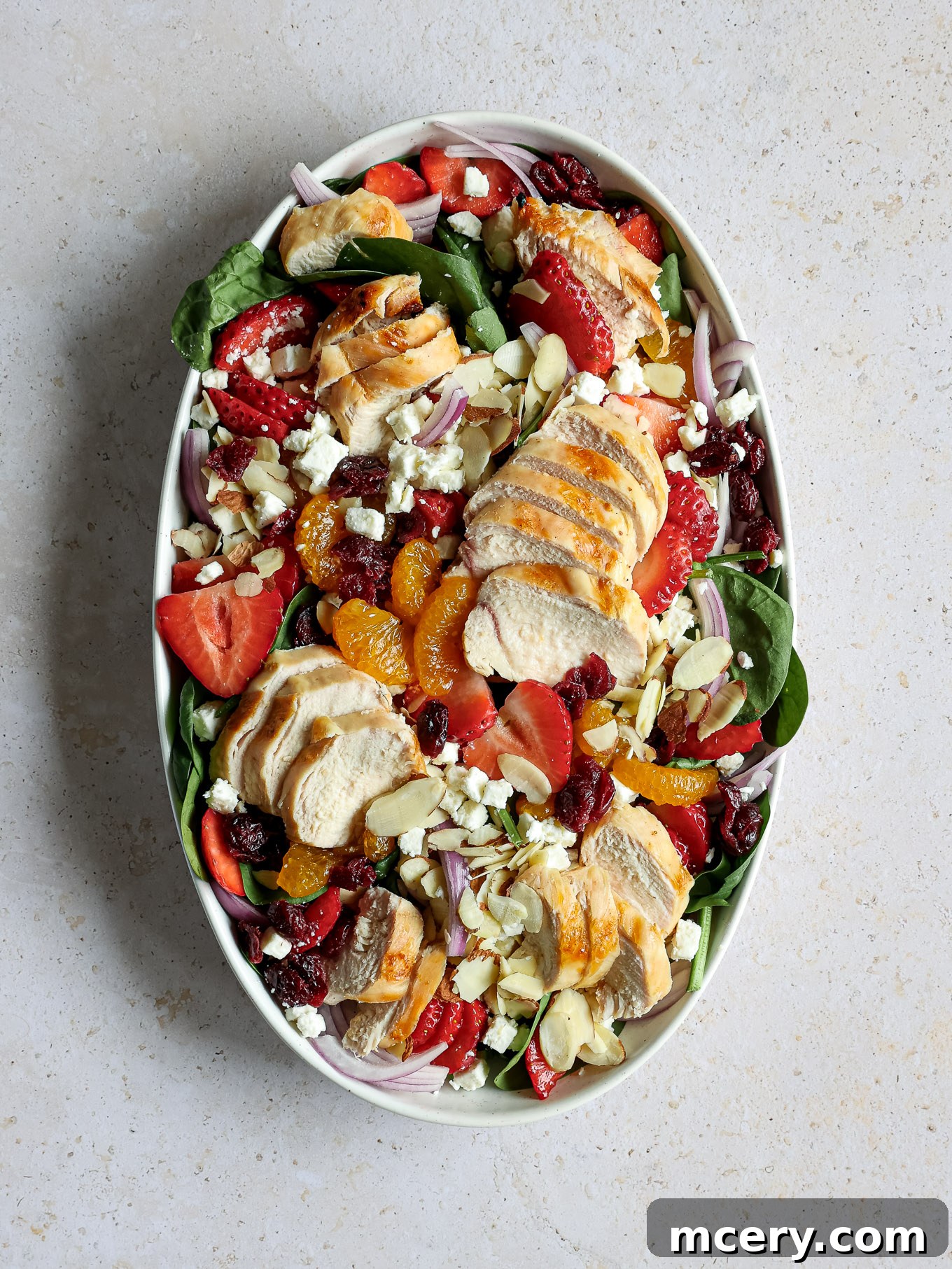Vibrant Strawberry Chicken Salad 5 Cooked, grilled chicken slices are beautifully arranged on top of the colorful spinach salad.