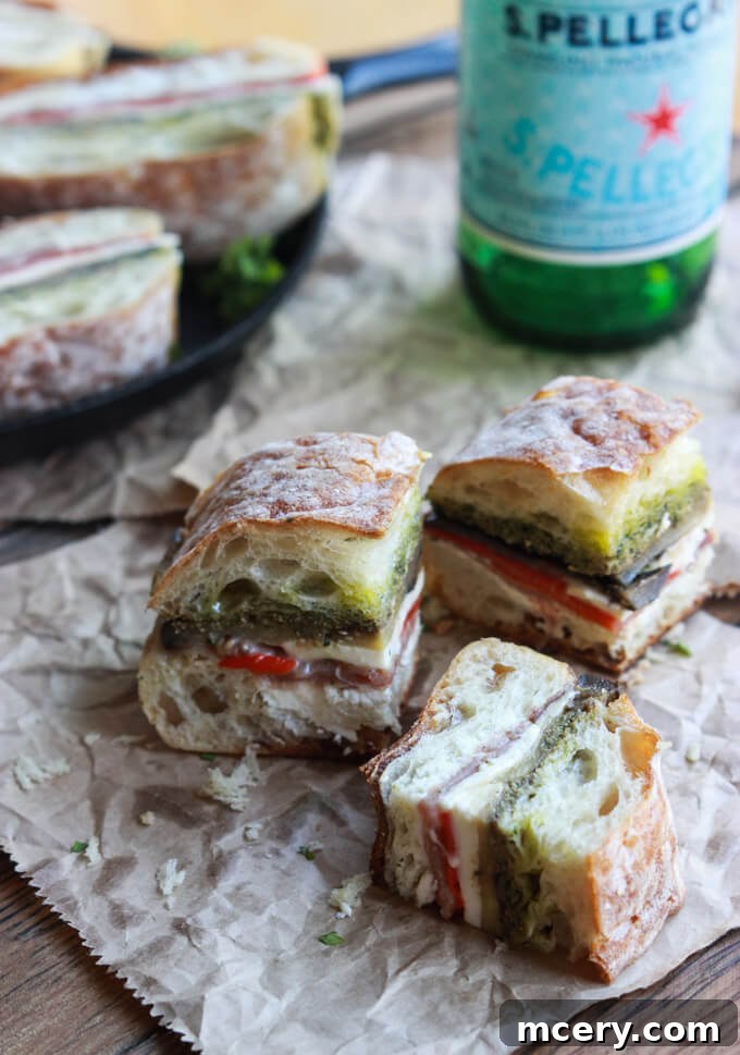 Italian Prosciutto Delight 4 A perfectly pressed ciabatta sandwich, cut into elegant portions, served alongside refreshing mineral water.