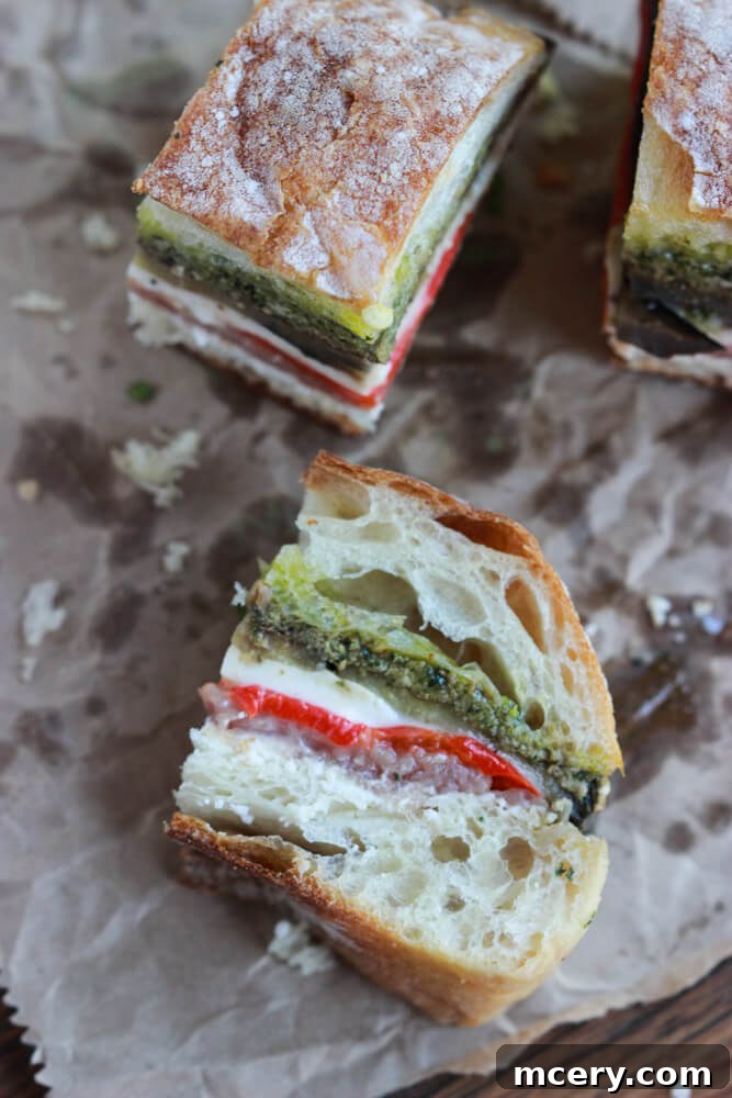Italian Prosciutto Delight 5 A meticulously cut pressed sandwich, laying on its side on parchment paper, showcasing its vibrant, tightly packed layers.