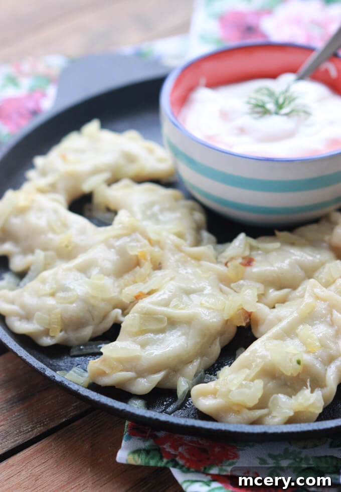 Pillowy Potato Pierogi 6 Beautifully plated potato perogies with caramelized onions and a generous dollop of sour cream, garnished with fresh dill.