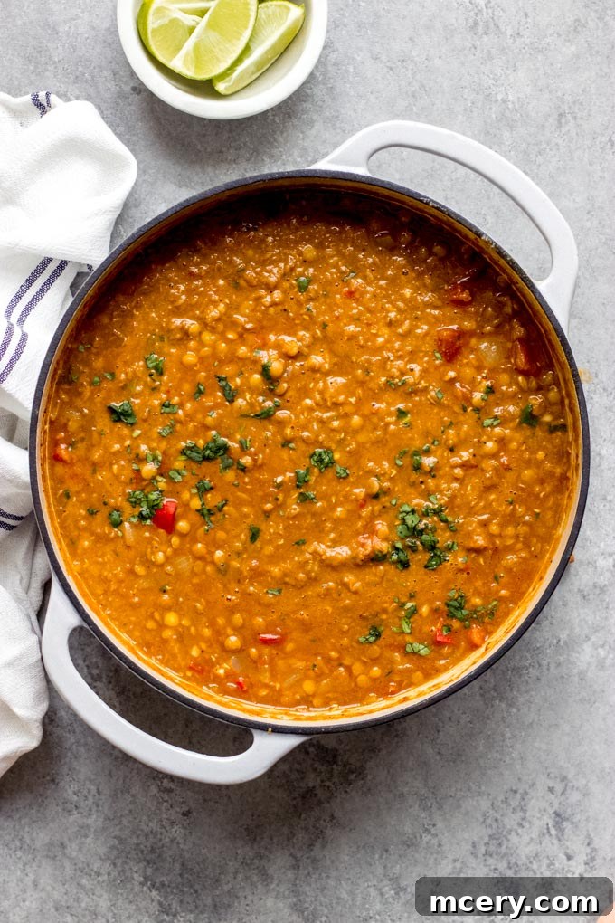 Plant-Powered Lentil Chili 9 A large pot of rich lentil chili without meat, garnished with fresh cilantro and lime wedges, ready to serve.