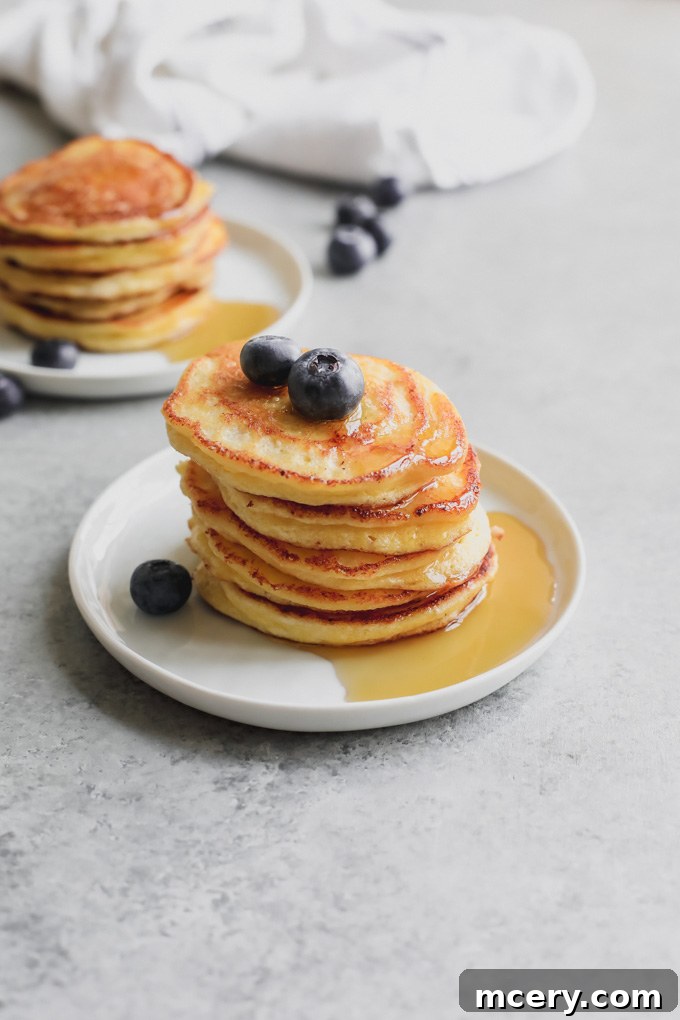 Pillowy Ricotta Pancakes 2 Delicious Fluffy Ricotta Hotcakes topped with fresh berries and maple syrup, ready to be served