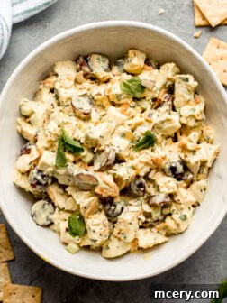 Creamy chicken salad with curry dressing, fresh herbs, and grapes in a bowl.