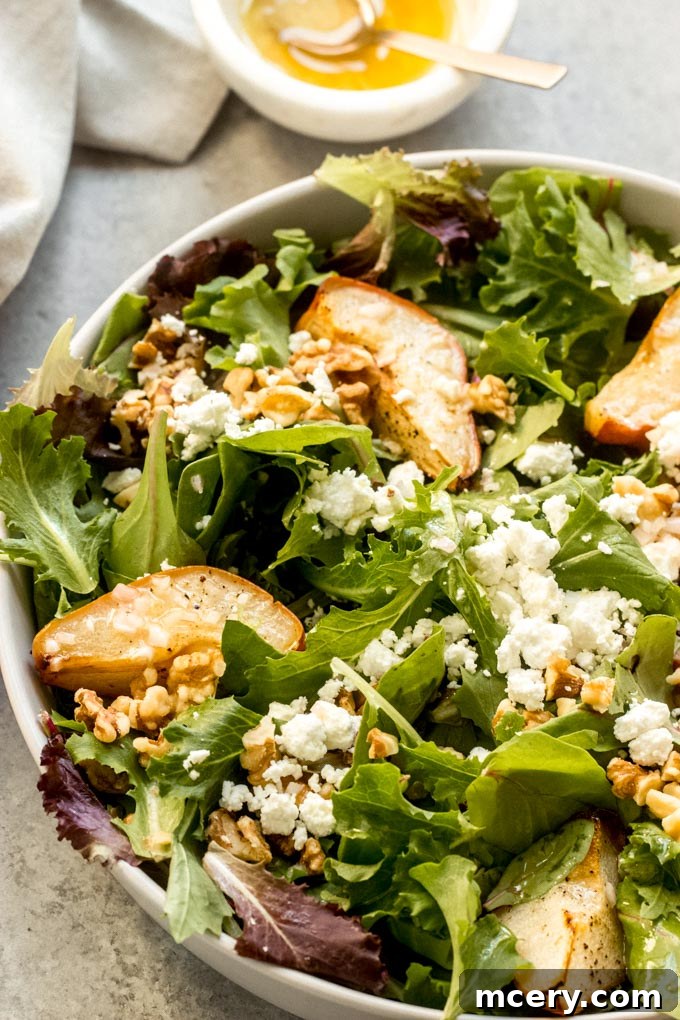Caramelized Pear & Chevre Salad 3 Close-up shot of a roasted pear and goat cheese salad, highlighting the tender texture of the pears and creamy goat cheese amidst green leaves