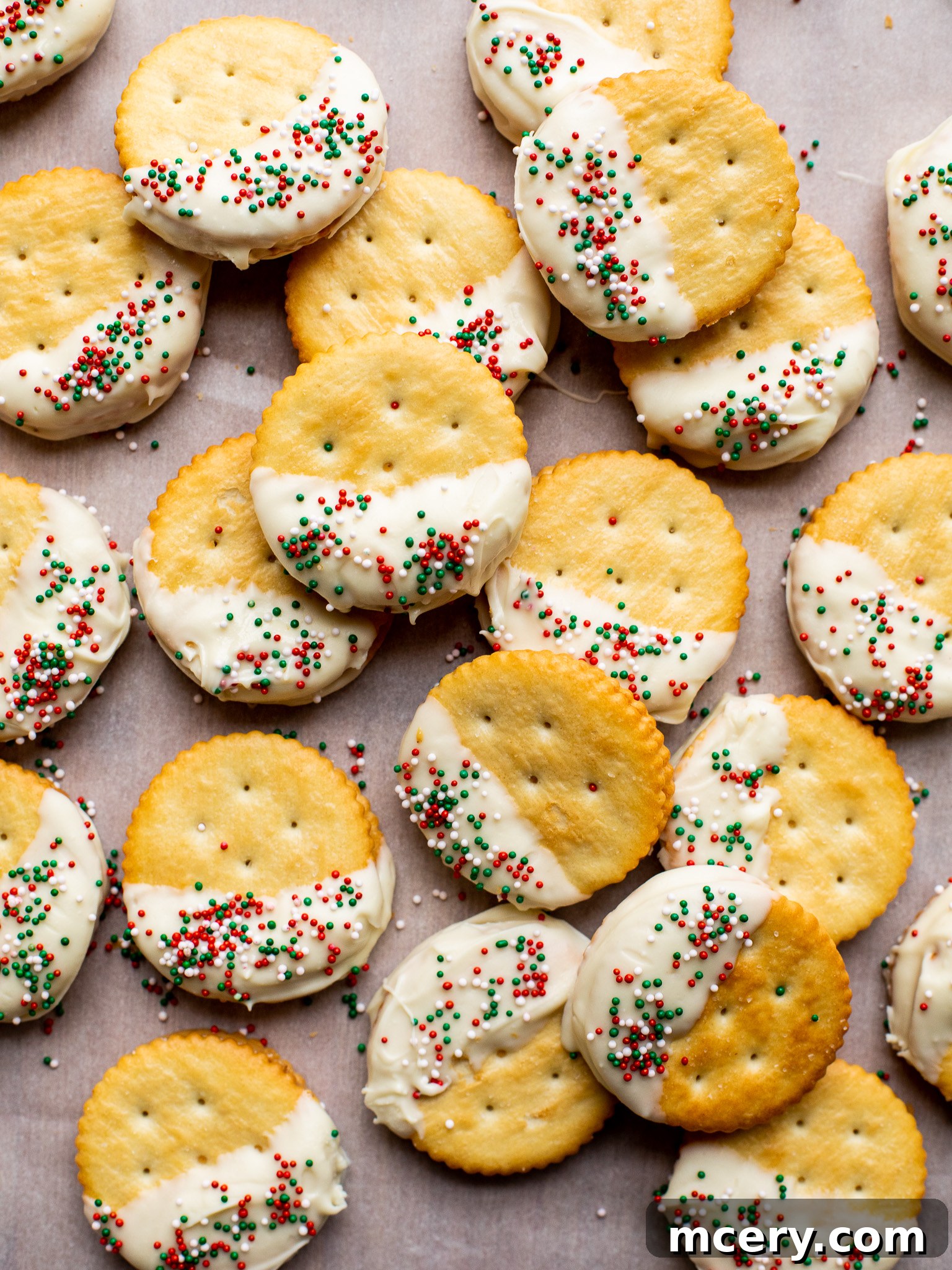 Golden Sweet Salty Cookie Crunch 6 A close-up shot of several finished no-bake Ritz Cracker Cookies, perfectly coated in white chocolate and adorned with colorful sprinkles, artfully arranged on a cooling rack.