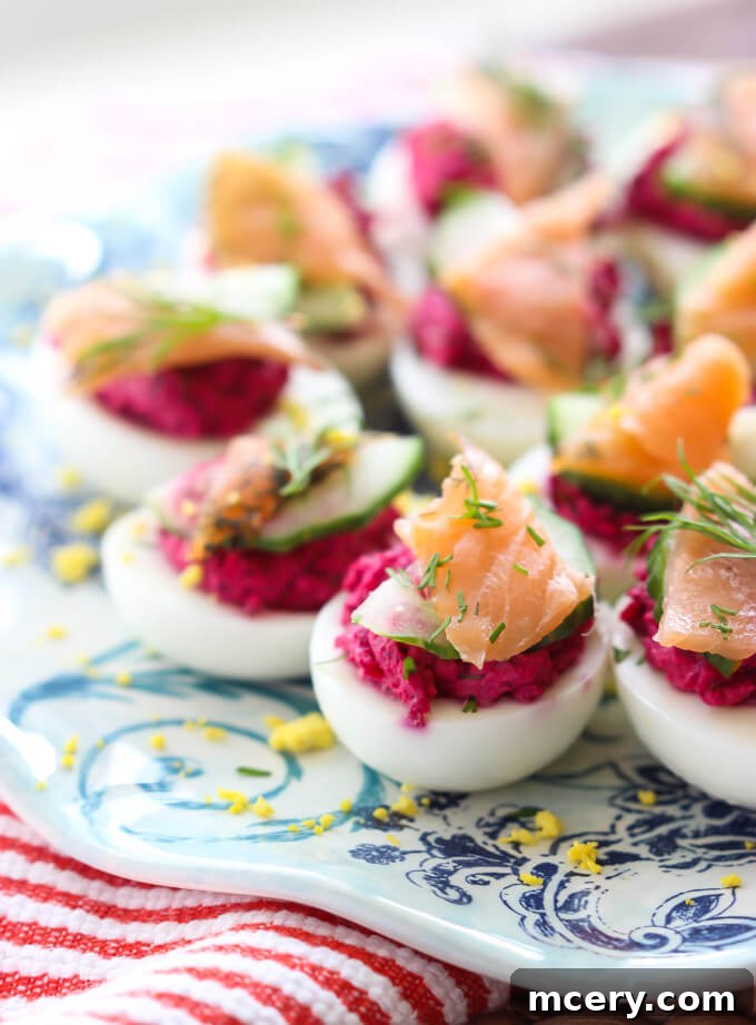 Gourmet Smoked Salmon Deviled Eggs 4 Vibrant deviled eggs with beetroot filling and smoked salmon, arranged beautifully on a serving platter. Perfect for holidays.