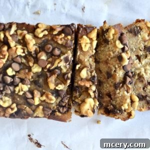 Perfectly Moist Gluten-Free Banana Bread 2 A sliced loaf of Gluten-Free Banana Bread topped with walnuts and chocolate chips on a white surface. The bread is light brown and looks moist, with a generous topping that adds texture and contrast, ready to be enjoyed.
