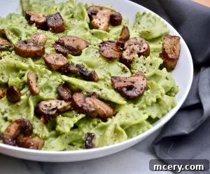 Creamy Vegan Basil Cashew Cream Sauce served with pasta and sautéed mushrooms, showcasing its rich texture.