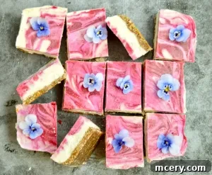 Close-up of a single No-Bake Lemon Raspberry Bar, showing the creamy lemon layer, the vibrant raspberry swirl, and the date-nut crust.